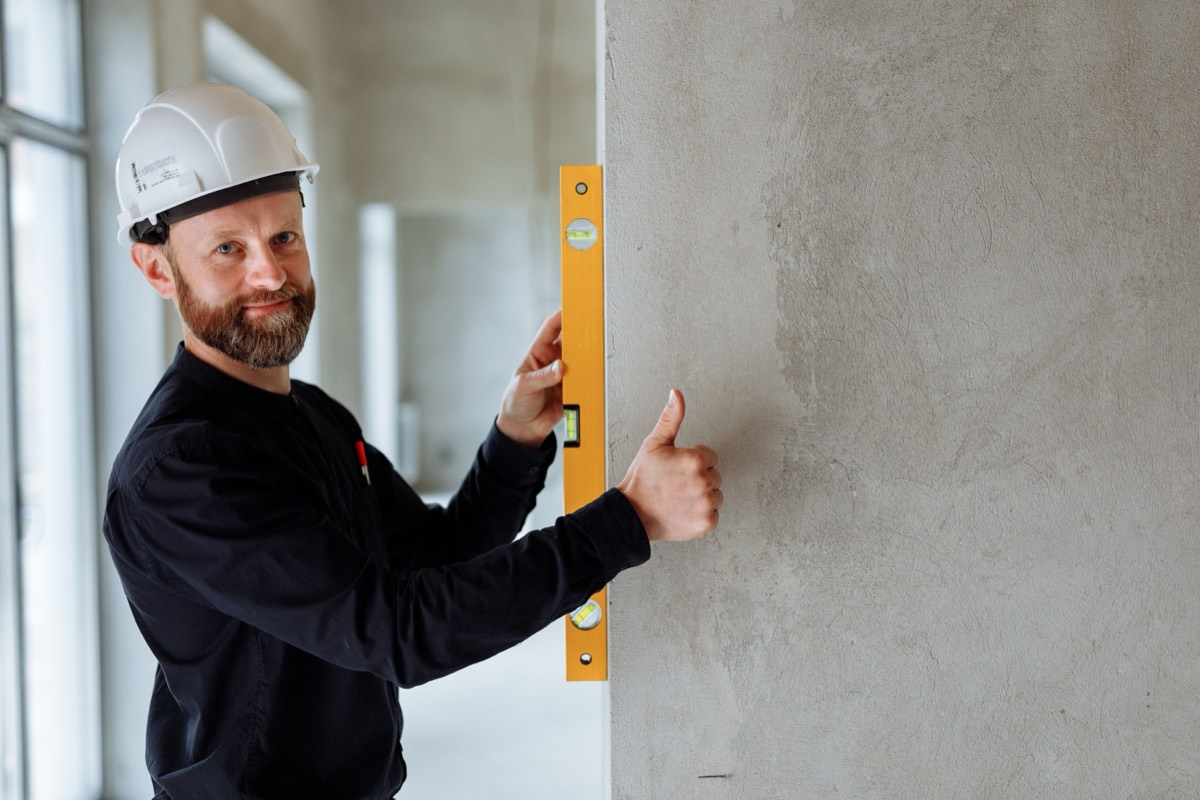 Licensed contractor in a hard hat checking measurements on a job site