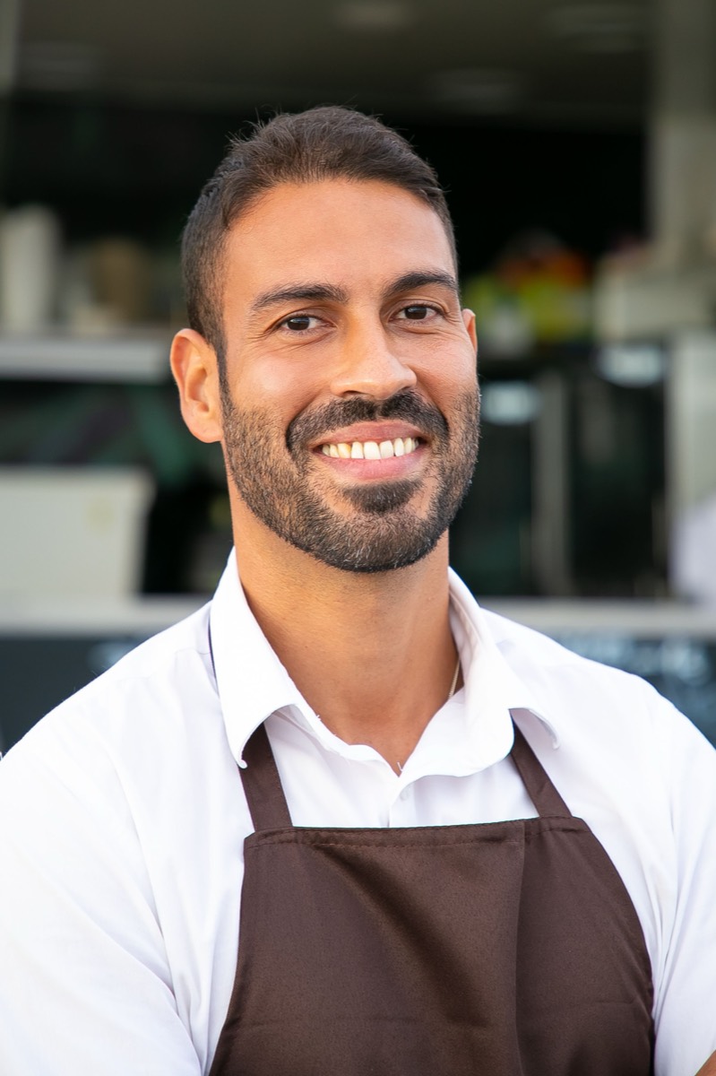 Smiling restaurant owner in an apron welcoming guests