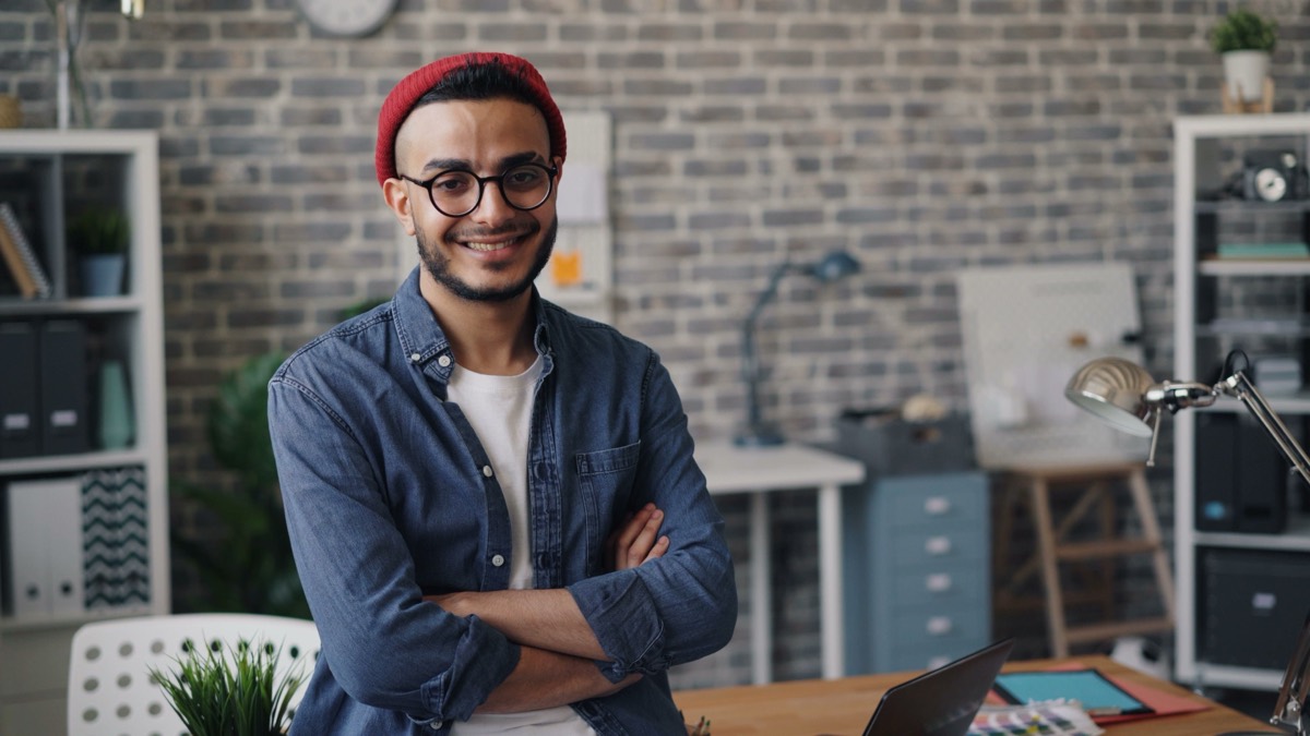 Confident Phoenix small business owner smiling with arms crossed in his office